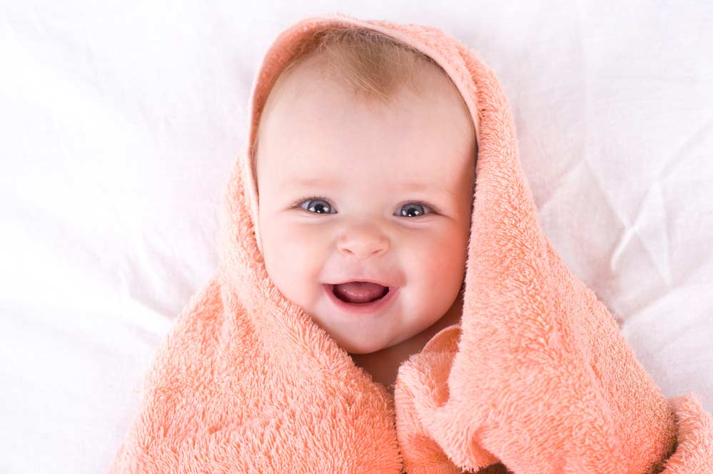 cute infant wrapped in peach towel